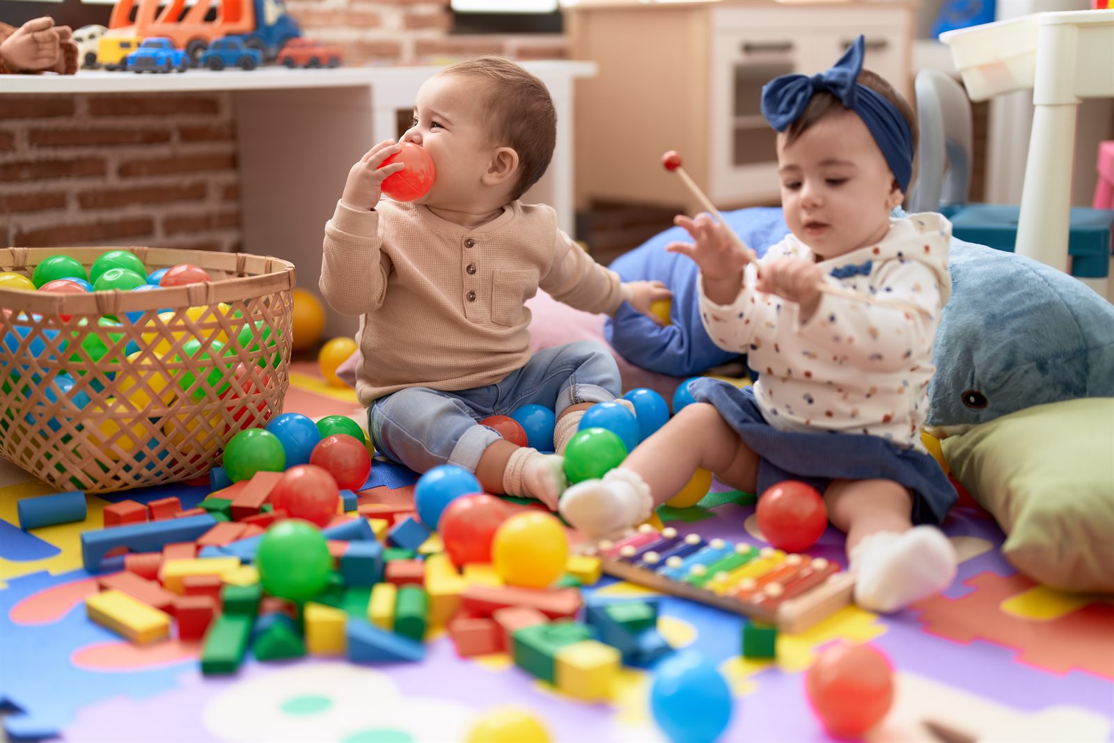 Deux enfants jouent avec des instruments et des ballons, assis au sol